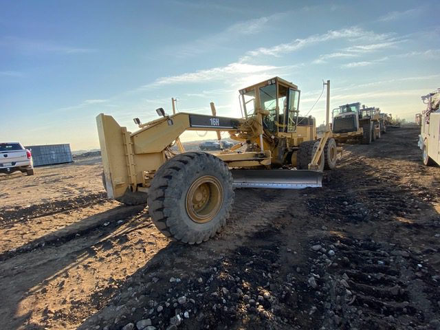 A yellow tractor is parked on the dirt.