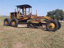1932-Cat-Motor-Grader A yellow and black tractor is parked in the grass.