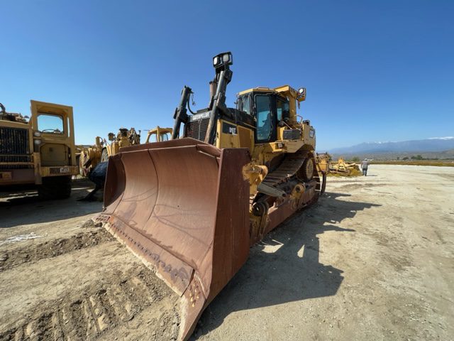 A yellow bulldozer parked in the dirt.