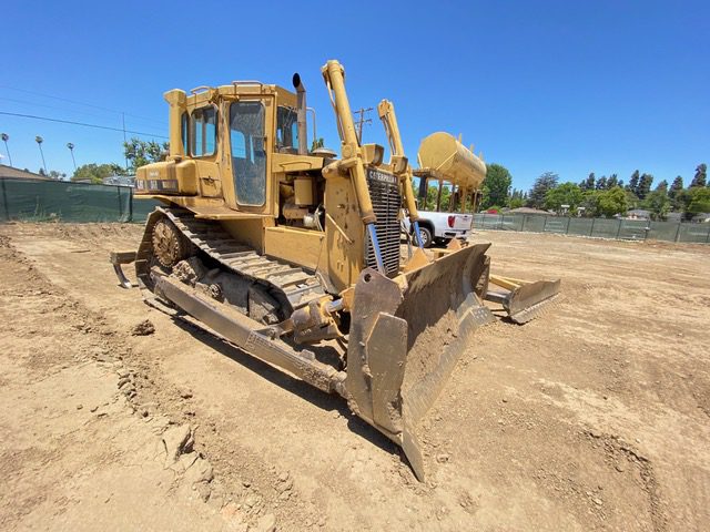 A yellow bulldozer sitting on top of a dirt field.