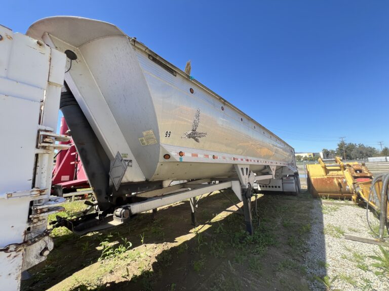 A large white trailer parked in the grass.